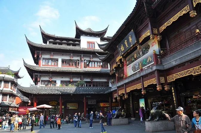 A crowded bazaar square in front of gilded traditional-style buildings