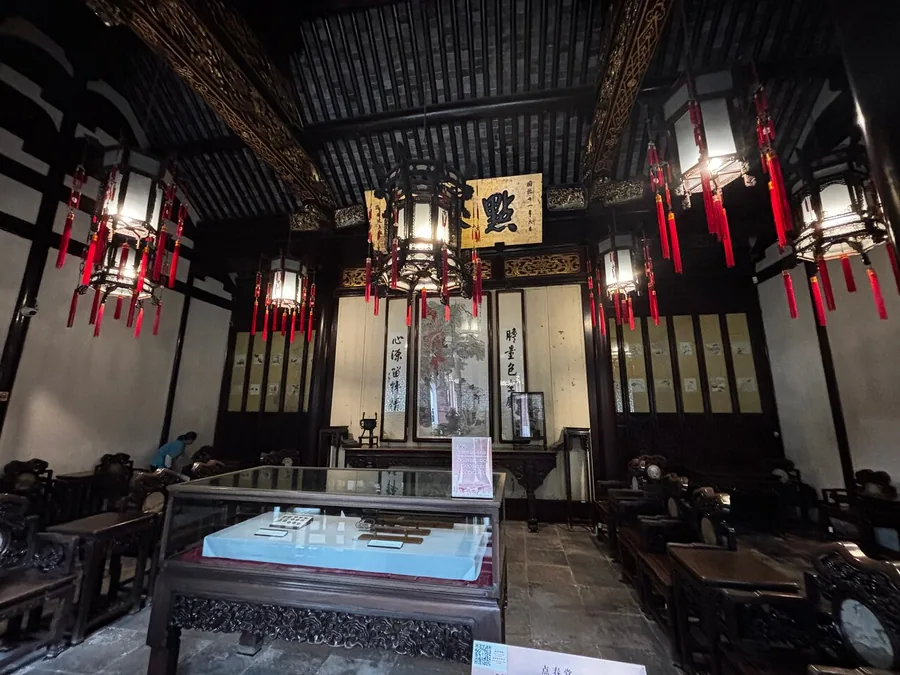 A dim hall inside Yu Garden with carved wooden furniture and hanging red-tasselled lanterns